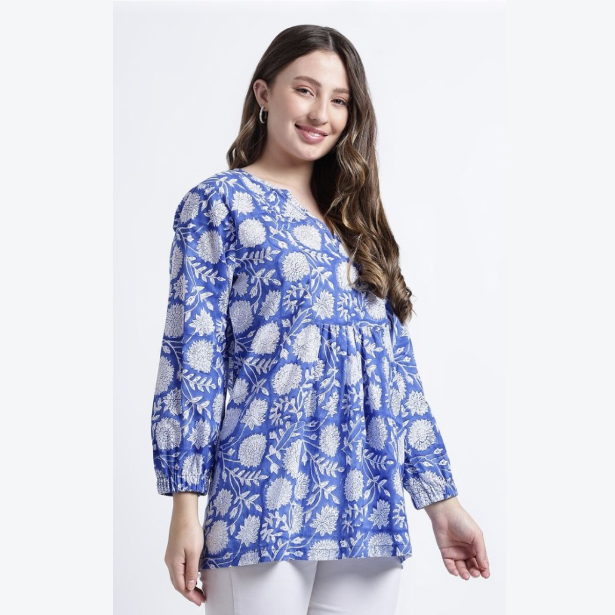 Greatest Good member Feature hIhandmade blue printed tunic Blue Printed Tunic: A smiling model wearing a bright blue tunic with white floral patterns. The garment features long sleeves and a loose, flowy fit, showcasing traditional textile craftsmanship.