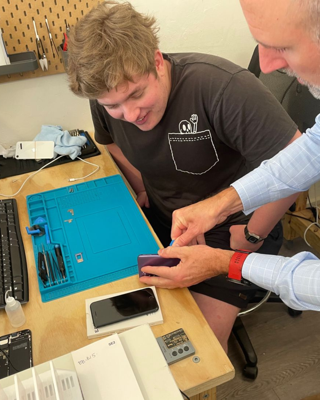 image of young man being taught how to refurbish phone